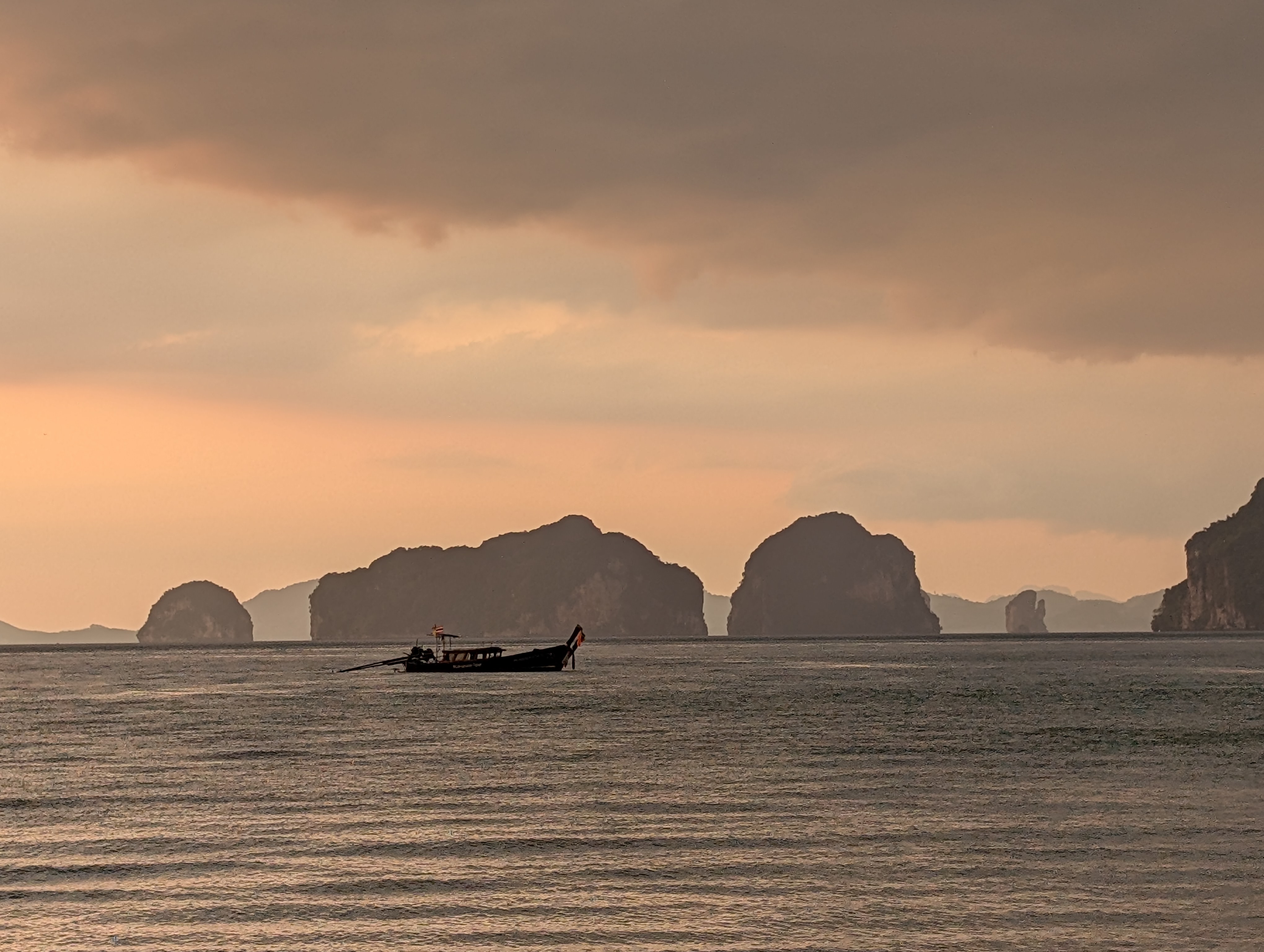 A long-tail boat silhouetted at dawn